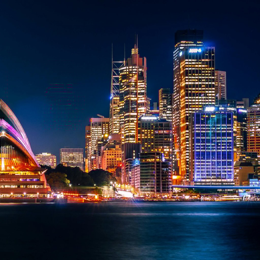 Stunning night view of Sydney Opera House and city skyline with vibrant lights.