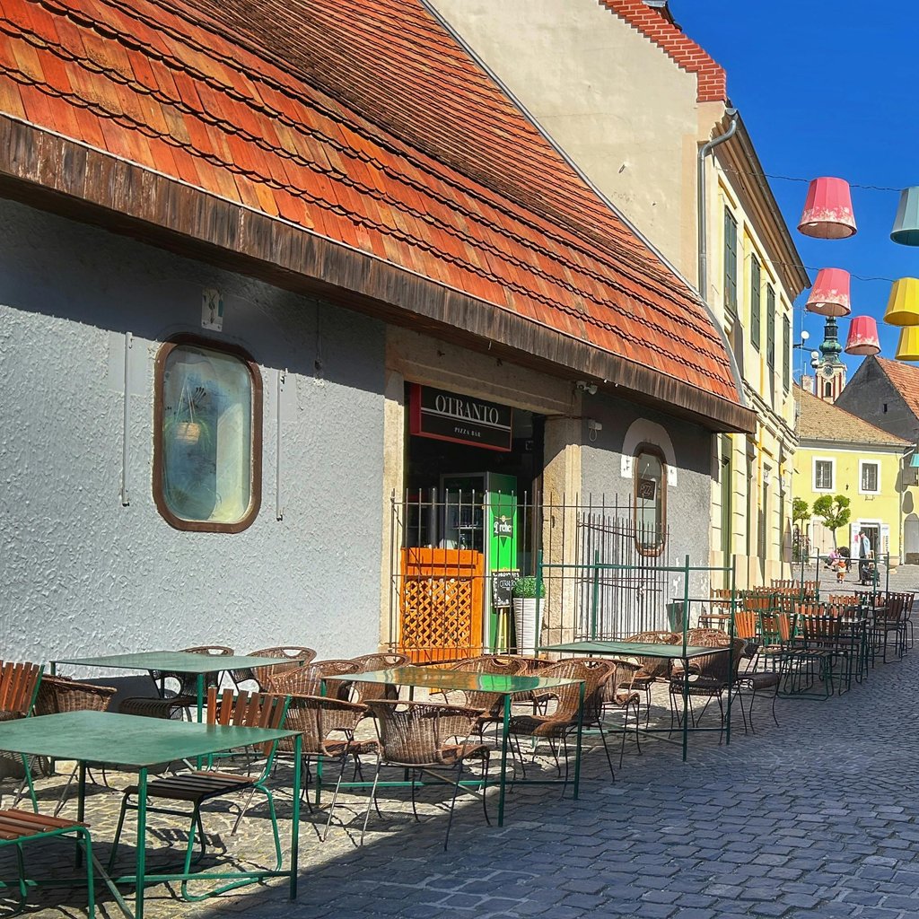 Explore a vibrant street in Szentendre, Hungary featuring colorful hanging decorations and charming architecture.