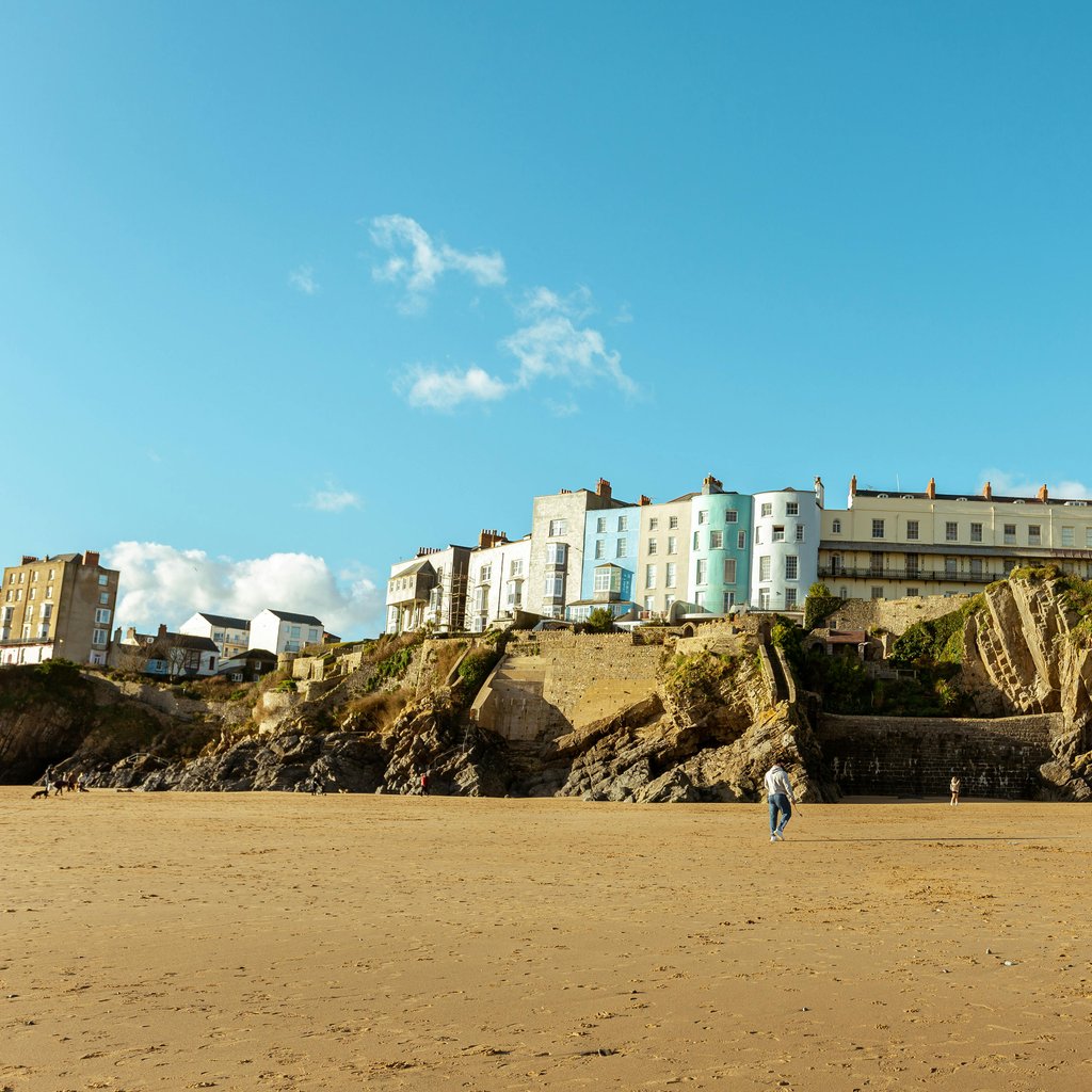 Picturesque view of coastal cliffs and buildings in Tenby, Wales under a clear blue sky.