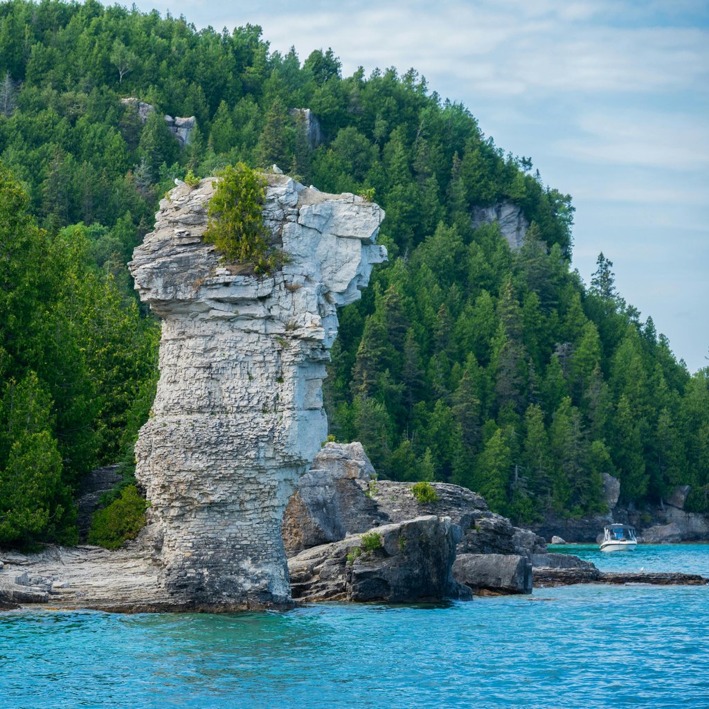 Explore the stunning rock formations of Flowerpot Island in Tobermory, Ontario, surrounded by lush forest and clear blue waters.