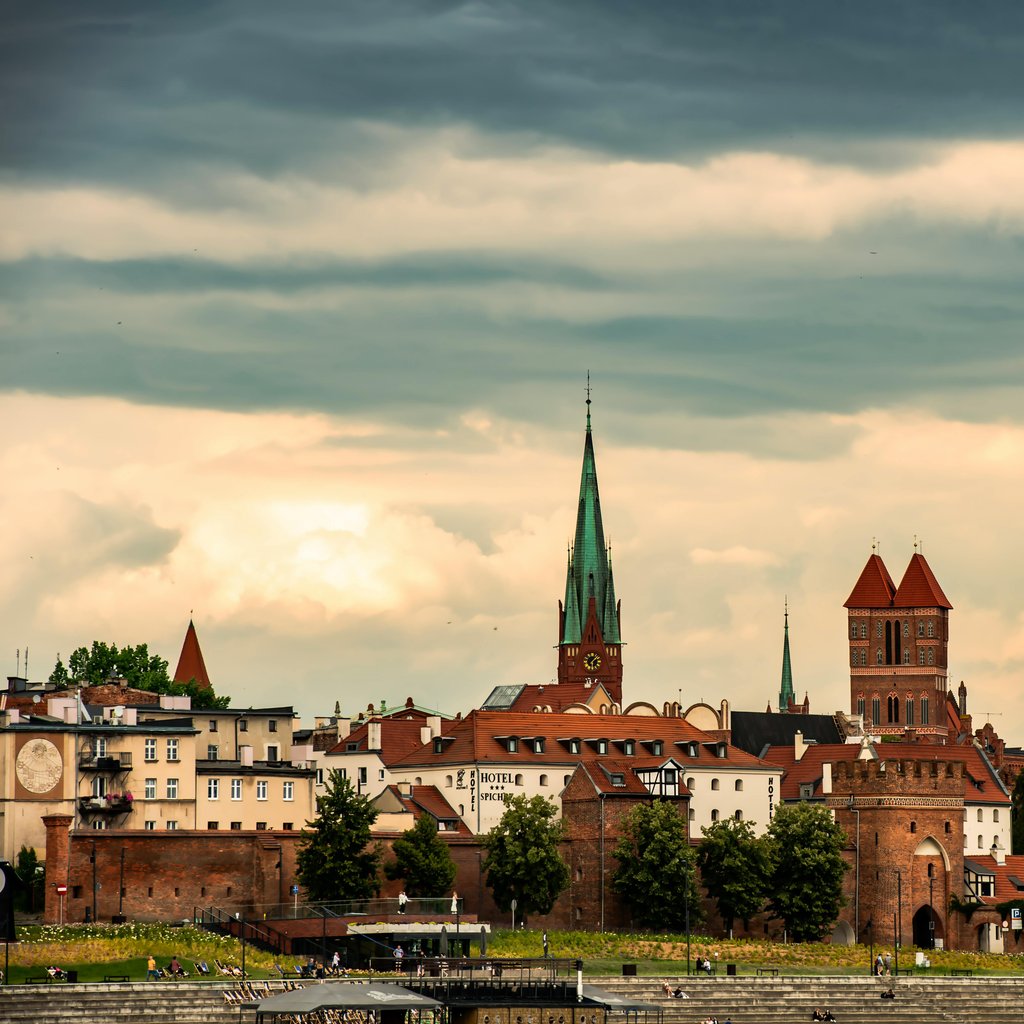 Beautiful sunset over Torun cityscape featuring historic buildings and church towers in Poland.