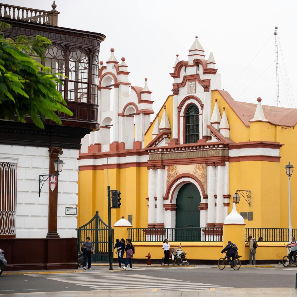 Vibrant yellow church in Trujillo, Peru, showcasing colonial architecture with street activity.