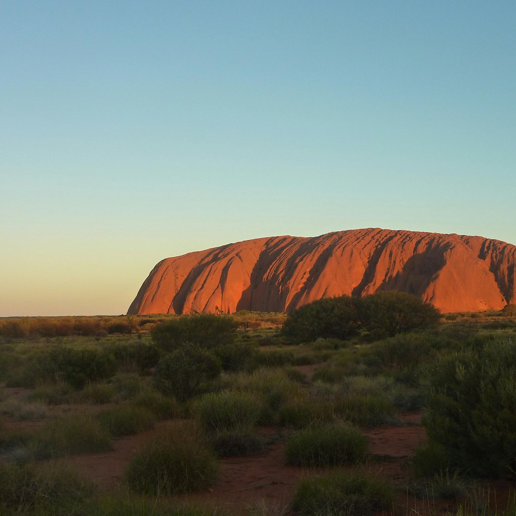Capture the majestic Uluru rock formation glowing under the sunset. A natural wonder in Australia's Outback.