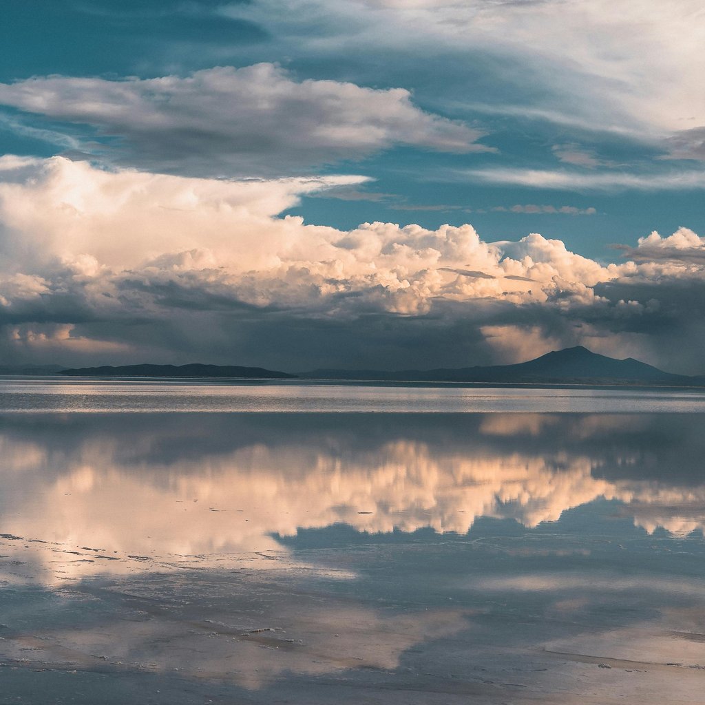 Capture the mesmerizing cloud reflections over the expansive Salar de Uyuni salt flats in Bolivia.