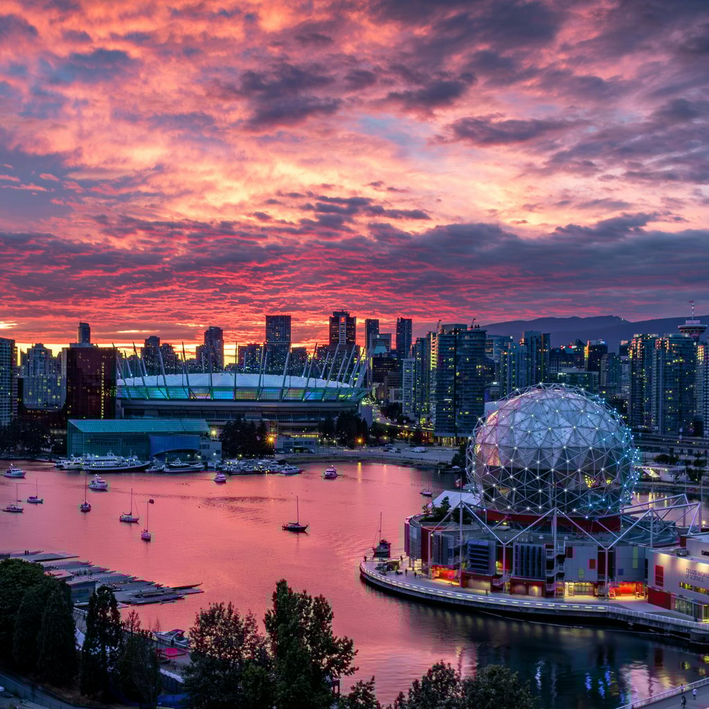 Stunning view of Vancouver cityscape with colorful sunset sky reflecting on harbor water.