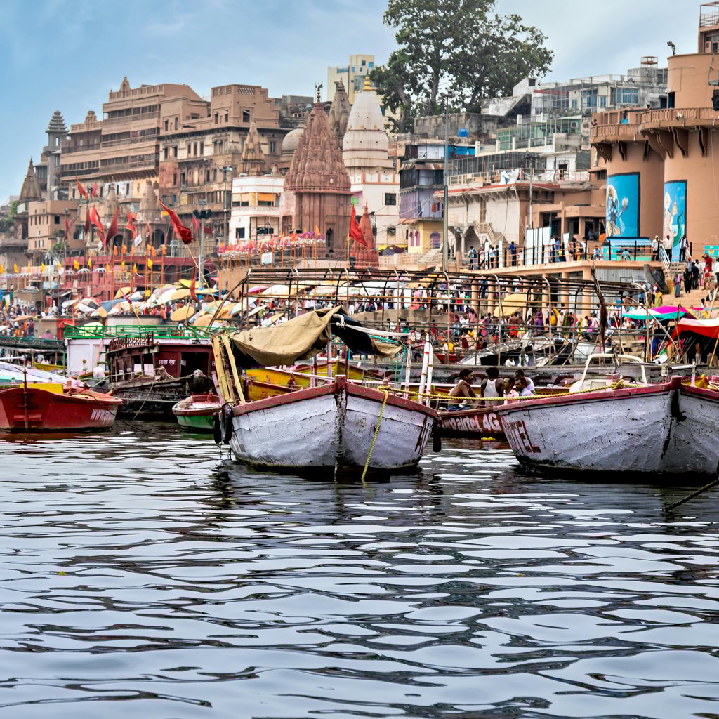 Vibrant boats aligned along Varanasi's iconic riverbank, showcasing urban life by the Ganges.