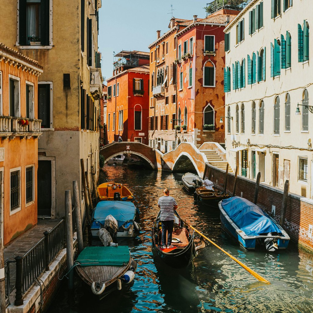 Charming canal scene in Venice with a gondola navigating under bridges.