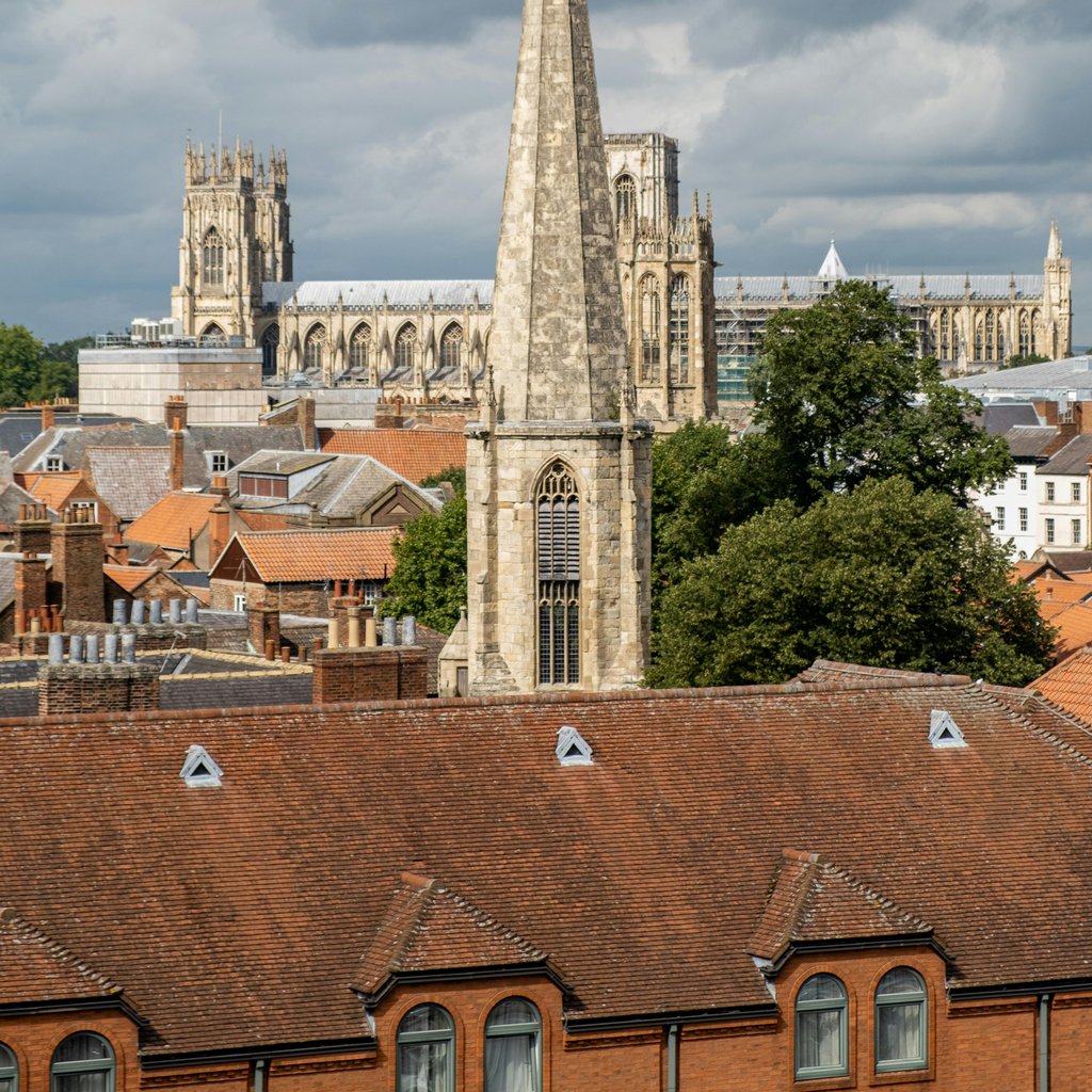 A stunning view of a historic cathedral with city rooftops under dramatic clouds.