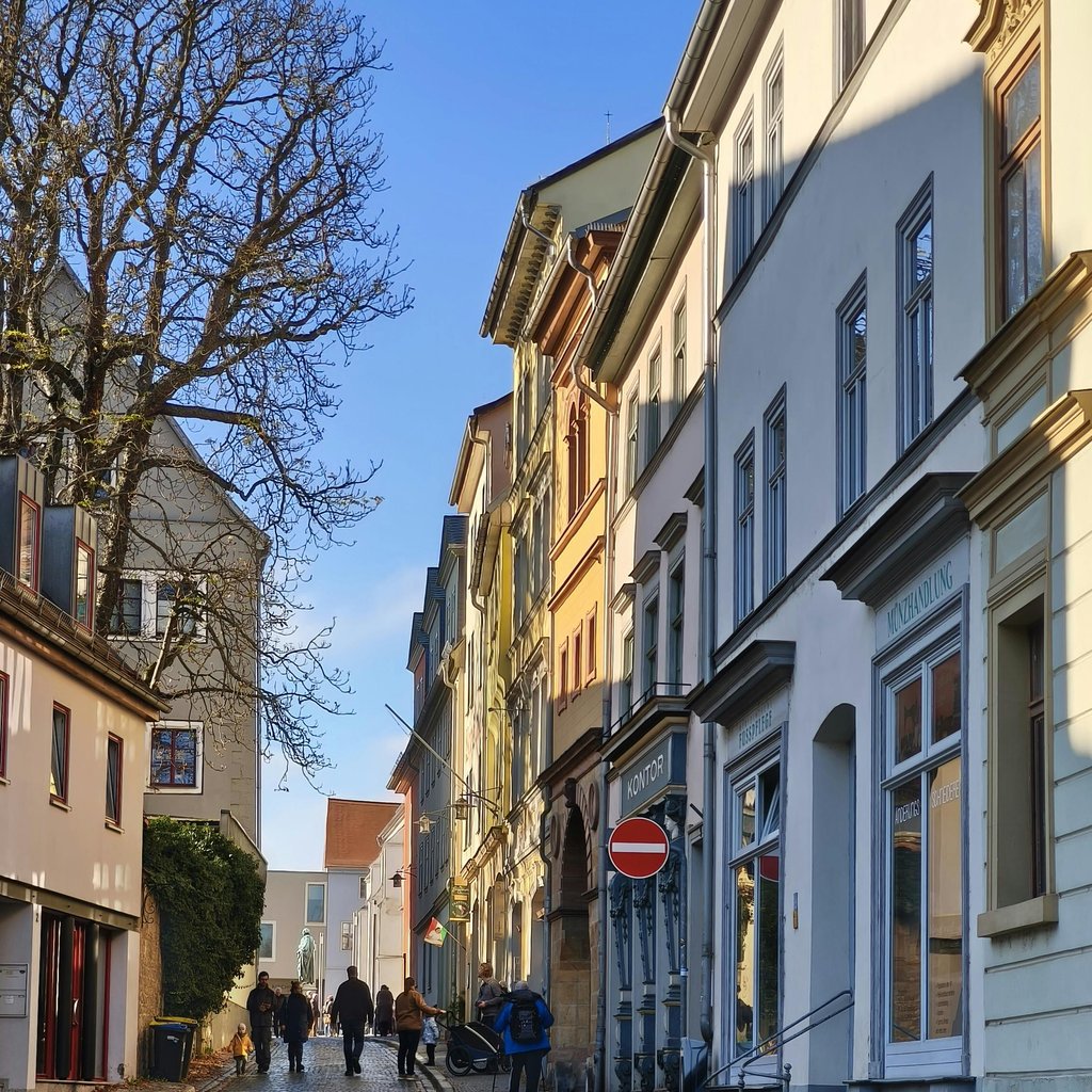 Historic Weimar street with people walking, showcasing classic European architecture.