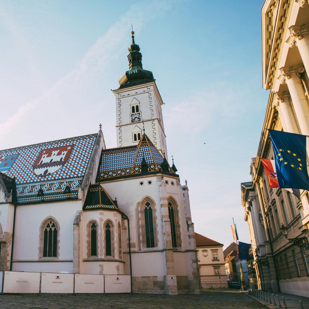 Beautiful view of St. Mark's Church and Town Square in Zagreb, Croatia under a clear blue sky.
