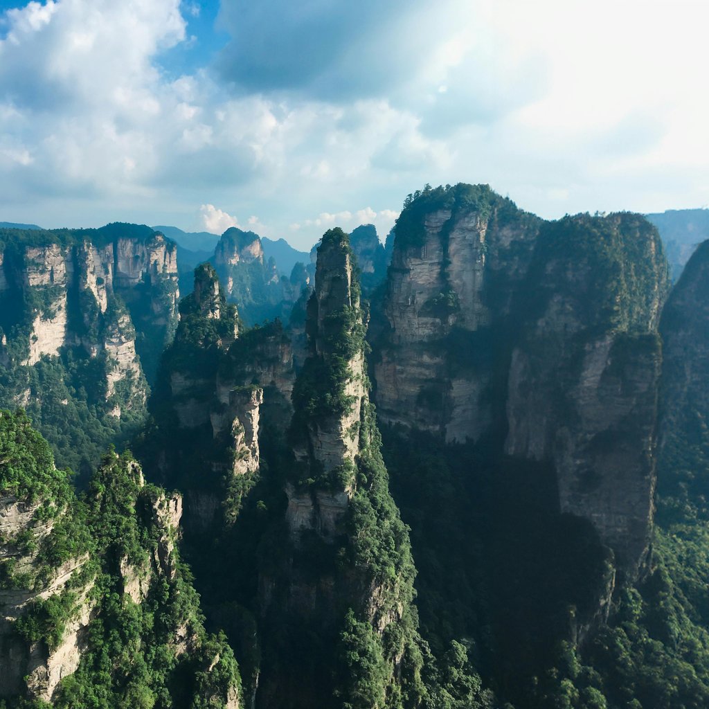 Explore Zhangjiajie's iconic pillar-like mountains under a stunning sky, a must-see for nature lovers.