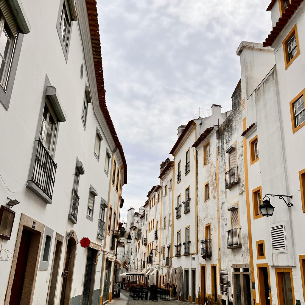 A picturesque alley in Évora, Portugal, featuring classic townhouses and cobblestone streets.