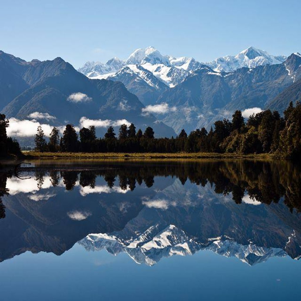 This photo is of Mount Aoraki (Mt. Cook) & Mount Tasman reflecting over Lake Matheson (New Zealand).  I took this photo, early morning, in November 2013 during a month-long trip to New Zealand.  The reflection is a near-mirror image of the sky, mountains and trees.