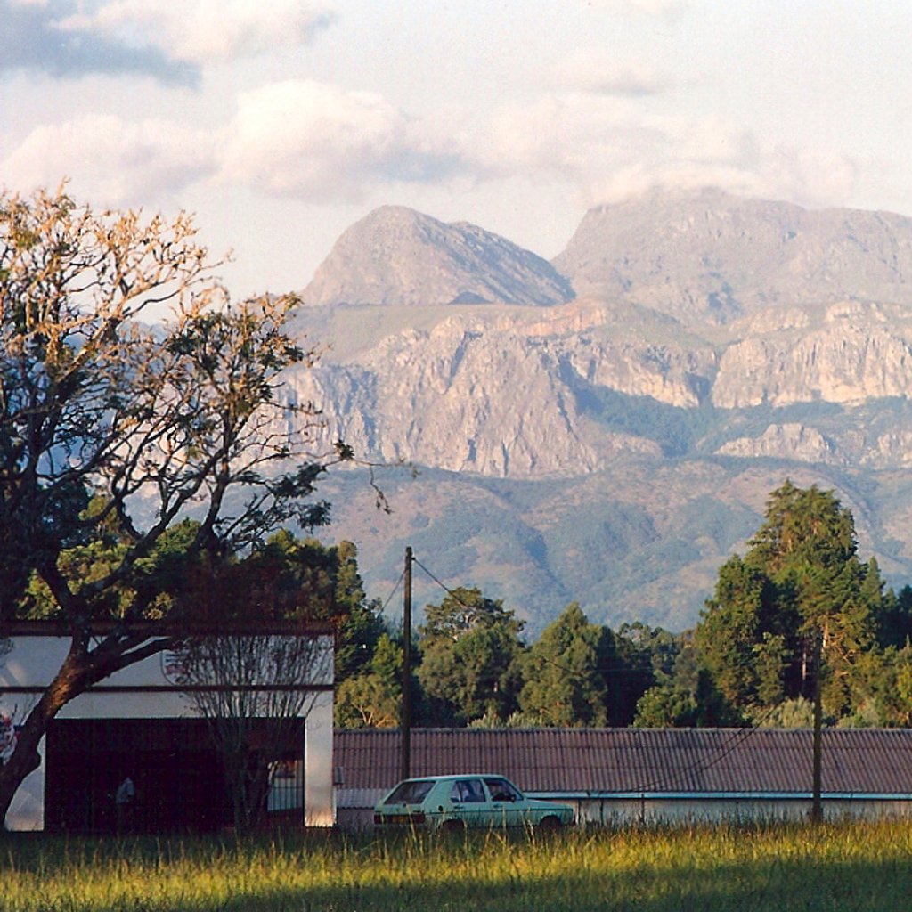The Eastern Highlands of Zimbabwe, seen from the village of Chimanimani, Manicaland. The mountains form the border with Mozambique. The roofline in the centre is a small parade of shops - the centre of the village. Taken April 1995 on Fujifilm.