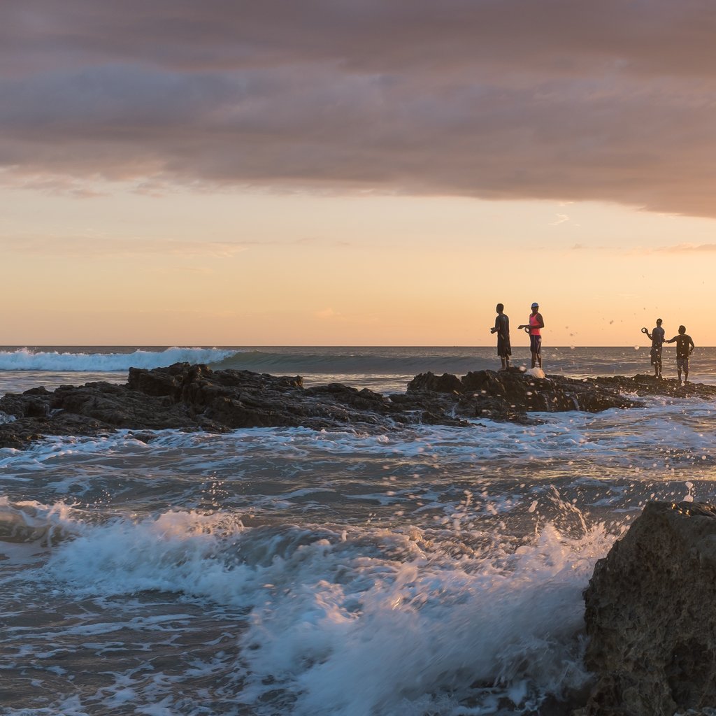 The slippery but sharp rocks and the waves constantly breaking on them make it for a dangerous playground. But it doesn't stop fishers to try their luck with a simple line until dark. Shot in Playa Santa Teresa, Costa Rica.